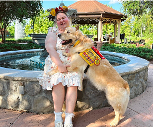 A guest in Minnie ears poses with a dog beside a garden fountain
